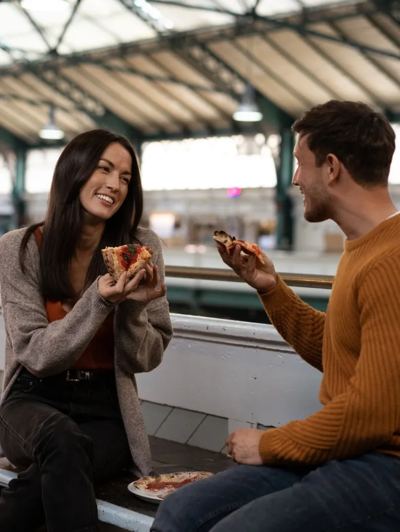 A couple enjoying pizza on a market terrace