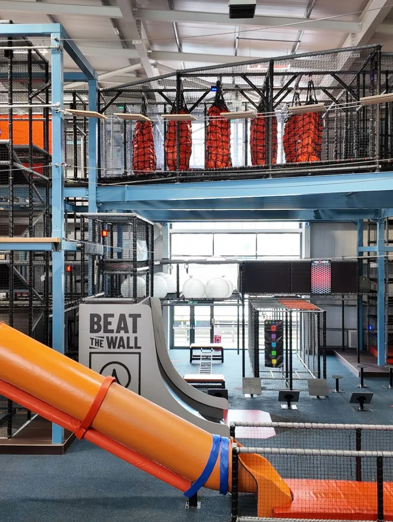 An indoor high ropes/assault course with slides, climbing frames and wires.