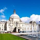 Exterior shot of Cardiff City Hall with clock tower, and fountains.