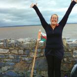Walker on the Wales Coast Path celebrating with hands in the air