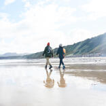 Couple walking on the beach at Porthdinllaen.