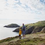 A man and child looking out to sea at Strumble Head, Pembrokeshire. 