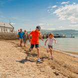 Family on beach at Beaumaris with pier in background.