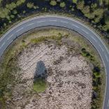 Image is an aerial shot of a car going around a bend on a road.