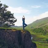Bild einer Frau, die Yoga auf einem Felsvorsprung macht.