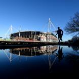 Principality Stadium which is reflected in the river with a jogger running by.