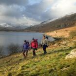 Drei Wanderer bei einem Spaziergang entlang des Sees Llynnau Mymbyr in Snowdonia.