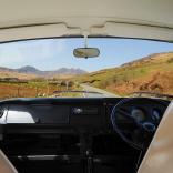 Inside view of camper van looking out of the front windscreen at the road and mountain scenery of Snowdonia.