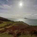 Image of Bardsey Island taken from the mainland with the sun shining above.