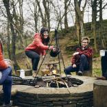 A group of people laughing round a campfire.