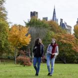 Zwei Frauen wandern durch einen herbstlichen Park.
