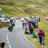 Cyclists and spectators lining a mountain road.