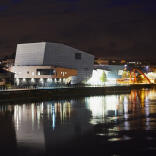 Ansicht des Riverfront Theatre und Arts Centre in Newport erleuchtet bei Nacht.