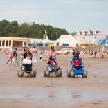 Three people using beach wheelchairs at Whitmore Bay beach.