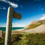 Wales coast path sign with sand dunes and sea in background