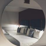 Two double beds reflected in a round mirror.