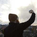 Ein Mann hält sein Handy in die Luft und macht ein Foto von Cardiff.