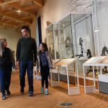 A family of three looking in museum cabinets.