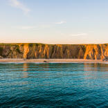 A sunset image of Marloes Cliffs and sea.