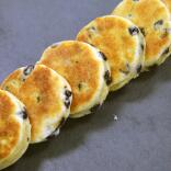 A row of welsh cakes lying on a slate grey surface. 