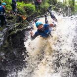 A man canyoning down rapids wearing safety gear.