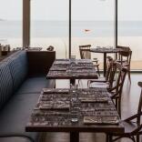 Interior of a restaurant, with view of sea.