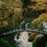 Couple standing on a bridge looking at waterfalls