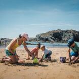 Two adults and two young children building sandcastles on a beach.