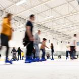 Indoor skating rink with people skating blurred action.