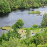 Aerial view of a lake with benches and wide gravelled pathways on the shore.