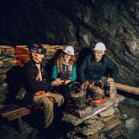 Three people wearing hard hats in an underground mine. 
