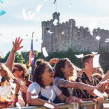 Audience at a music gig in Tafwyl standing behind a barrier with confetti in the foreground and Cardiff Castle in the background.