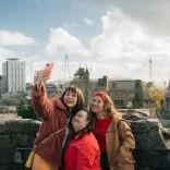 Grŵp o ffrindiau yn tynnu hunlan gyda'r ddinas yn y cefndir