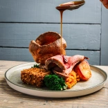 Cinio rhost ar blât mewn bwyty. Mae cig eidion, llysiau a phwdin swydd Efrog i'w weld.