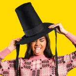 Menyw yn gwisgo het Gymreig ac yn sticio ei thafod allan