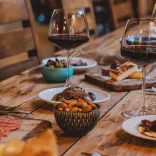 wooden table with tapas dishes and glasses of red wine.