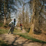 Two people mountain bikes on trail in bike park.