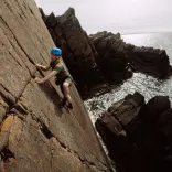climbing wearing helmet climbing sea cliff.