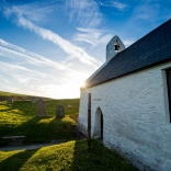 Sunny image of the side of a small whitewashed church.