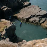 Coasteering - a person jumping into the sea from a cliff.