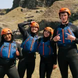 Four people in coasteering kit looking very happy. 