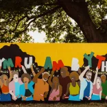 A colourful mural with loads of people holding up 'Cymru am byth' letters.