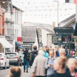 Visitors strolling through Hay-on-Wye during a lively day, with bookshops and bunting lining the street