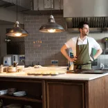 Person preparing food at a kitchen island in a modern restaurant kitchen.