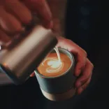Barista pouring milk into a cup of coffee