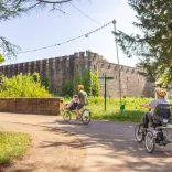 A family cycling in a city centre park with a castle in the background.