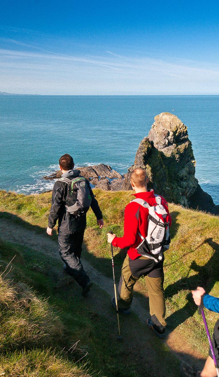 Three male walkers on Wales Coast Path, Pembrokeshire, West Wales