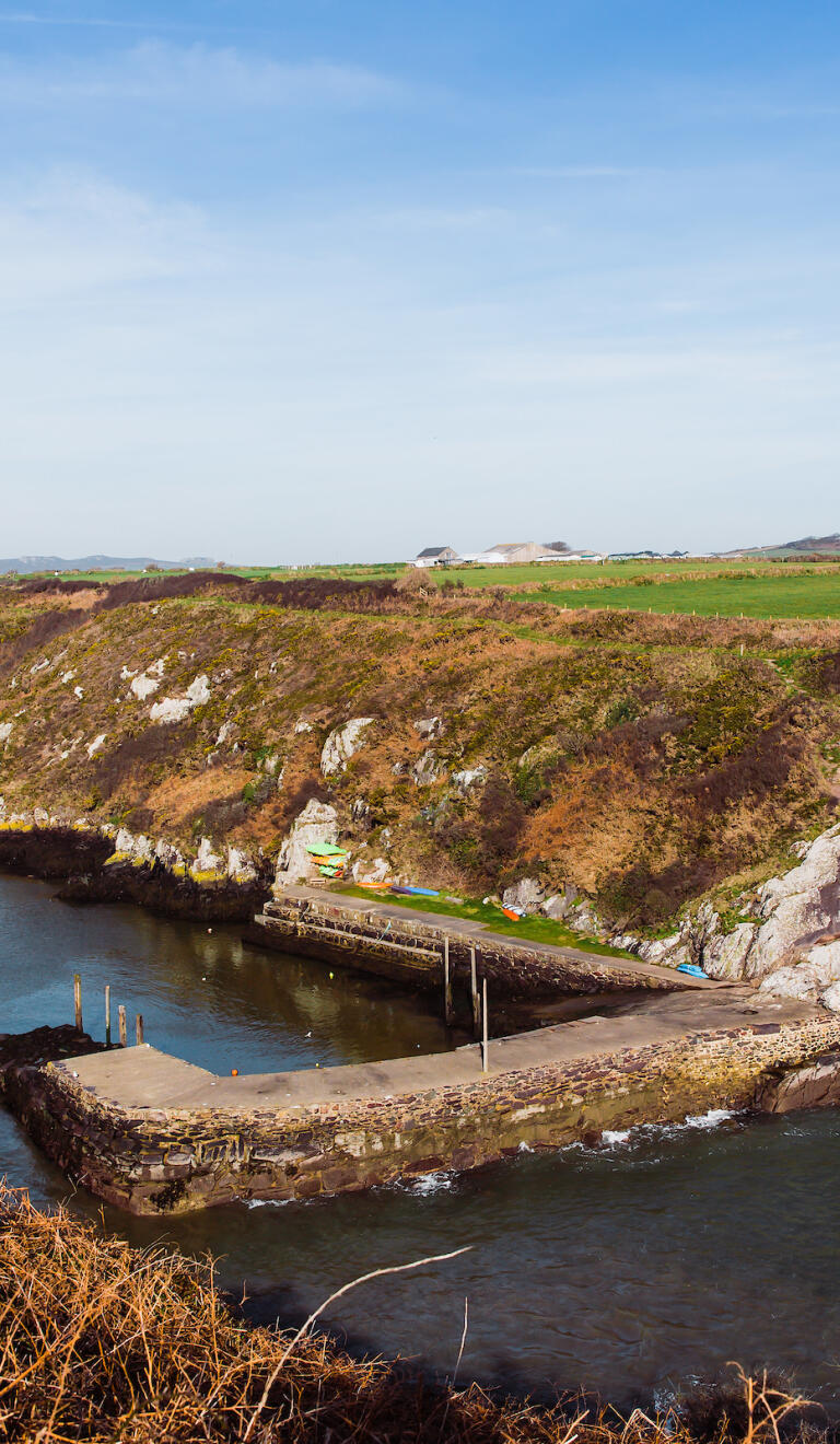 A small harbour surrounded by cliffs with the tide in.