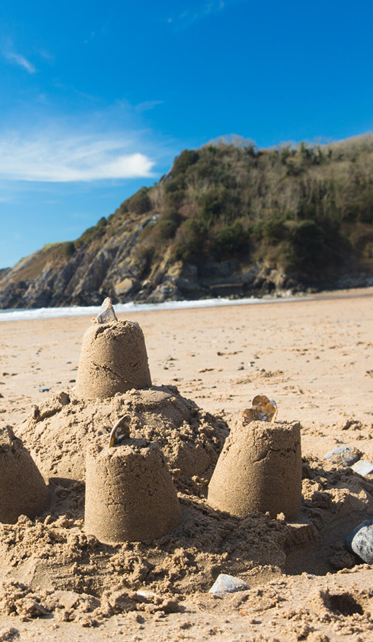Sandcastles on the beach with the sea and sky in the distance.