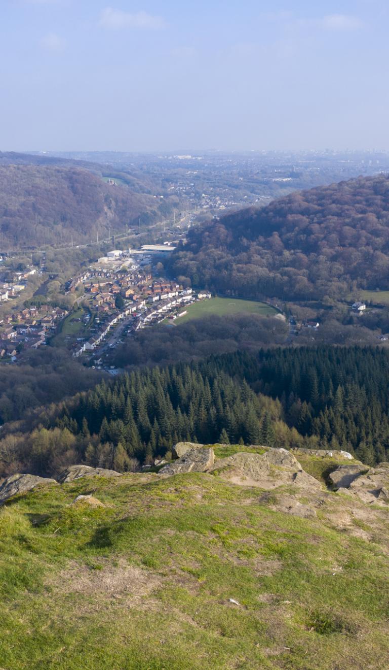 View from top of a mountain looking over houses and woodland.